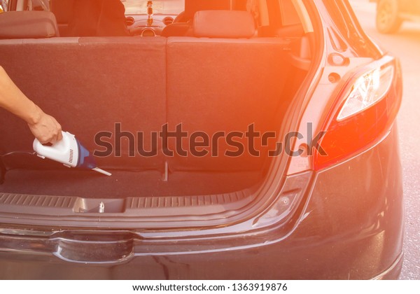 People\
holding car vacuum cleaners, vacuuming in\
cars.