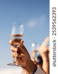 People holding champagne flutes at outdoor formal event and in a congratulatory cheers