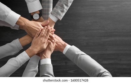 People Holding Hands Together Over Grey Wooden Background, Top View. Unity Concept