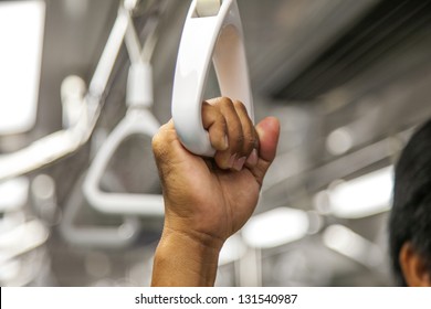 people holding onto a handle on a train.