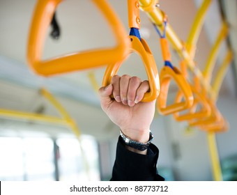 people holding onto a handle on a train.