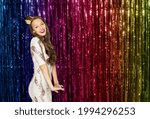 people, holidays and celebration concept - happy young woman or teen girl in party dress and princess crown over rainbow foil fringe curtain background