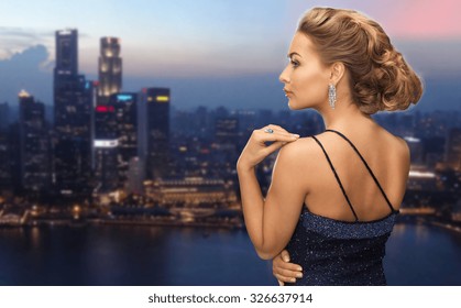 People, Holidays, Jewelry And Glamour Concept - Beautiful Woman With Diamond Earring Over Night Singapore City Background