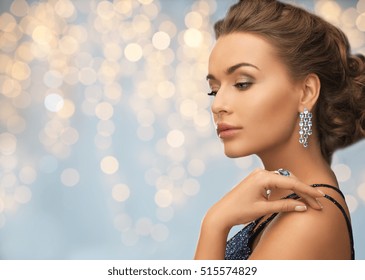 People, Holidays, Jewelry And Luxury Concept - Woman In Evening Dress With Diamond Earring Over Lights Background