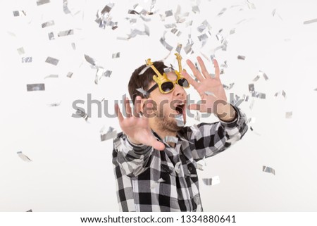 People, holidays and party concept - funny guy in glasses dancing in confetti on white background
