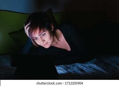 People Hooked Up With Entertainment Devices Before Going To Bed. Young Woman Watching Online Tv Show In Bed At Night. Technology And Leisure Concept. Lifestyle At Home For Young People.