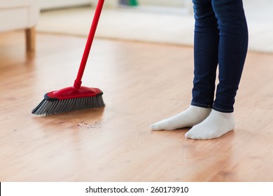 people, housework, cleaning and housekeeping concept - close up of woman legs with broom sweeping floor at home - Powered by Shutterstock