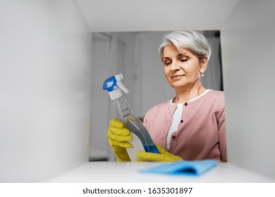 People, Housework And Housekeeping Concept - Happy Senior Woman Cleaning Rack And Reading Label On Detergent At Home