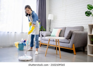 People, housework and housekeeping concept - Happy Asian woman or housewife with mop cleaning floor and dancing at home.