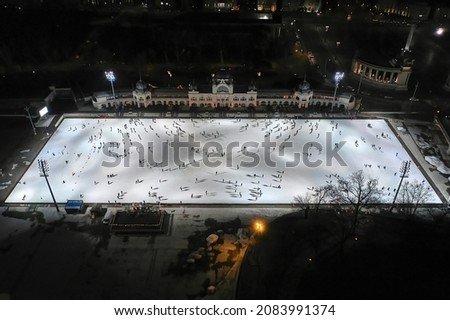 People ice skating on a large ice rink in Budapest, aerial top down view from high angle