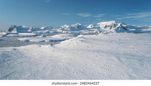 People jogging winter slope in snow-covered landscape. Antarctica wild nature scene, enjoy winter activity in mountains. Travel, active lifestyle, sport, recreation in arctic sunny day. Aerial view - Powered by Shutterstock