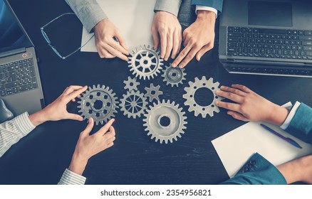 People joining cog wheel on the black desk. - Powered by Shutterstock