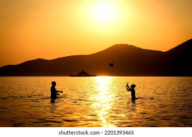 People kids boy man playing with ball in lake sunset with blur mountain in background  - Shutterstock ID 2201393465