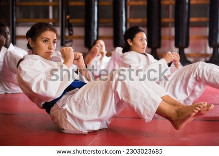 People in kimono warming up before karate training. They're doing stretching exercises for legs