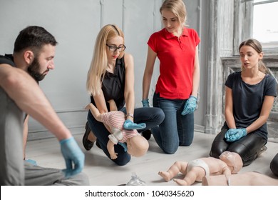People learning how to safe a life when the baby is choked sitting together with instructor during the first aid training indoors