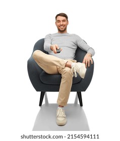 People And Leisure Concept - Happy Smiling Man With Tv Remote Control Sitting In Chair Over White Background