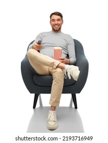 People And Leisure Concept - Happy Smiling Man With Tv Remote Control And Popcorn Sitting In Chair Over White Background