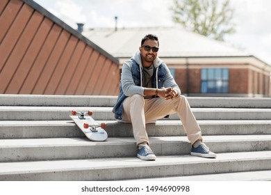 people and leisure concept - smiling indian man with skateboard sitting on stairs on city roof top - Powered by Shutterstock