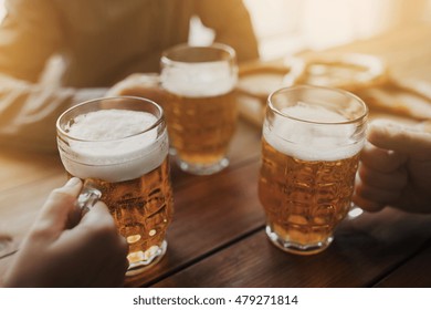 People, Leisure And Drinks Concept - Close Up Of Male Hands Clinking Beer Mugs At Bar Or Pub