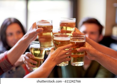 people, leisure, friendship and celebration concept - happy friends drinking draft beer and clinking glasses at bar or pub - Powered by Shutterstock