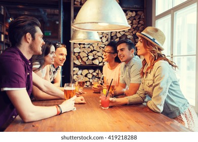 People, Leisure, Friendship And Communication Concept - Group Of Happy Smiling Friends Drinking Beer And Cocktails Talking At Bar Or Pub