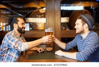 People, Leisure, Friendship And Party Concept - Happy Male Friends Drinking Draft Beer At Bar Or Pub And Clinking Glasses