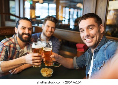 People, Leisure, Friendship, Technology And Bachelor Party Concept - Happy Male Friends Taking Selfie And Drinking Beer At Bar Or Pub