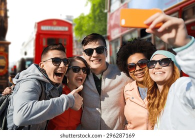 people, leisure, friendship and technology concept - group of smiling teenage friends taking selfie with smartphone over london city street background - Powered by Shutterstock