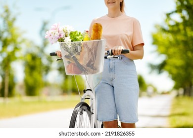 People, Leisure And Lifestyle - Close Up Of Happy Woman With Food And Flowers In Basket Of Bicycle On City Street