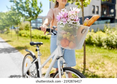 People, Leisure And Lifestyle - Close Up Of Happy Woman With Food And Flowers In Basket Of Bicycle On City Street