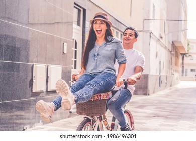 People, leisure and lifestyle concept happy young couple riding bicycle in the city - overjoyed young woman enjoy love and friendship with black boyfriend having fun - Powered by Shutterstock