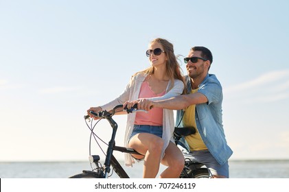 people, leisure and lifestyle concept - happy young couple riding bicycles on beach - Powered by Shutterstock