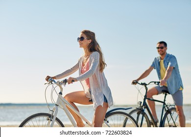 people, leisure and lifestyle concept - happy young couple riding bicycles on beach - Powered by Shutterstock