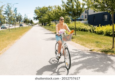 People, Leisure And Lifestyle - Happy Young Woman With Food And Flowers In Basket Of Bicycle On City Street