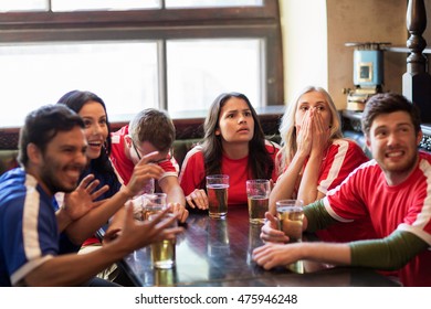 People, Leisure, Rivalry And Sport Concept - Friends Or Football Fans Drinking Beer And Watching Soccer Game Or Match At Bar Or Pub