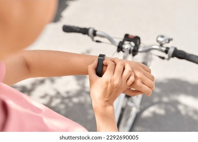 people, leisure and sport - close up of woman with smart watch riding bicycle on city street - Powered by Shutterstock