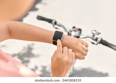 people, leisure and sport - close up of woman with smart watch riding bicycle on city street - Powered by Shutterstock