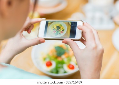 People, Leisure And Technology Concept - Close Up Of Woman Hands With Smartphone Taking Picture Of Food At Restaurant