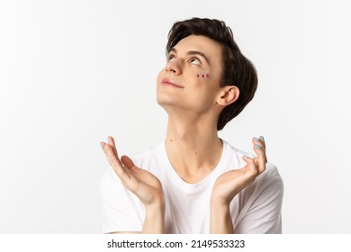 People, Lgbtq And Beauty Concept. Close-up Of Handsome Androgynous Man With Glitter On Face And Polished Fingernails, Looking Dreamy Up And Smiling, White Background