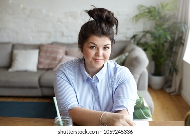 People, Lifestyle, Excess Weight And Body Positivity Concept. Cute Attractive Friendly Looking Young Woman In Her Twenties Sitting At Wooden Desk, Smiling Happily While Working Remotely At Home Office