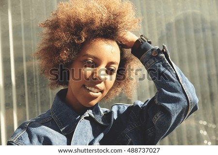 Similar – Young black woman, afro hairstyle, smiling near a wall in the street