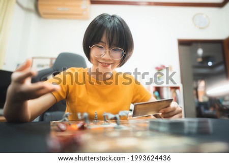 People lifestyle with interesting hobby at home concept. Young adult asian woman playing board game on top table. Happy with smile face and eye looking at camera.