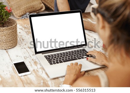 People, lifestyle, modern technology and communication concept. Young Caucasian female writer keyboarding on laptop while working on her new article for online women's magazine. View form back