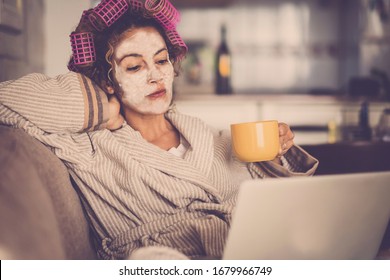 People Lockdown At Home Concept For Coronavirus Emergency Worldwide Pandemic - Woman At Home With Beauty Face Mask Looking The Web With Laptop For News