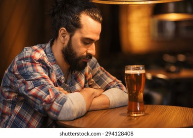 People, Loneliness, Alcohol And Lifestyle Concept - Unhappy Single Man With Beard Drinking Beer At Bar Or Pub