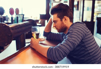 People, Loneliness, Alcohol And Lifestyle Concept - Unhappy Single Young Man In Hat Drinking Beer At Bar Or Pub