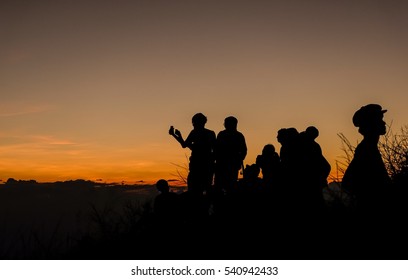 People looking for sunset on top of mountain. Silhouette photo background.