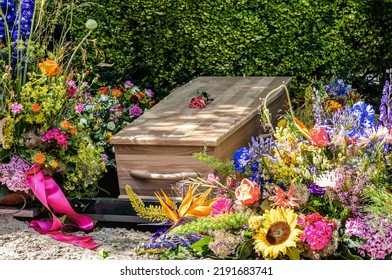 People loss and mourning concept, a  wooden coffin with beautiful flowers arrangement before funeral or burial at cemetery, a funeral service.  - Shutterstock ID 2191683741