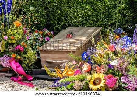 People loss and mourning concept, a  wooden coffin with beautiful flowers arrangement before funeral or burial at cemetery, a funeral service. 