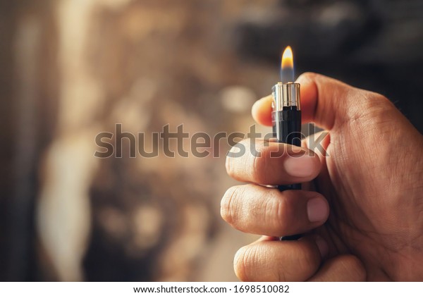 people man hand holding\
burning gas lighters arson conflagration damage background.\
Portable device used to create a flame. Safety and Set fire to\
insurance concept. 